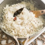 Basmati rice cooked with cumin, cinnamon stick and bay leaf in the pan.