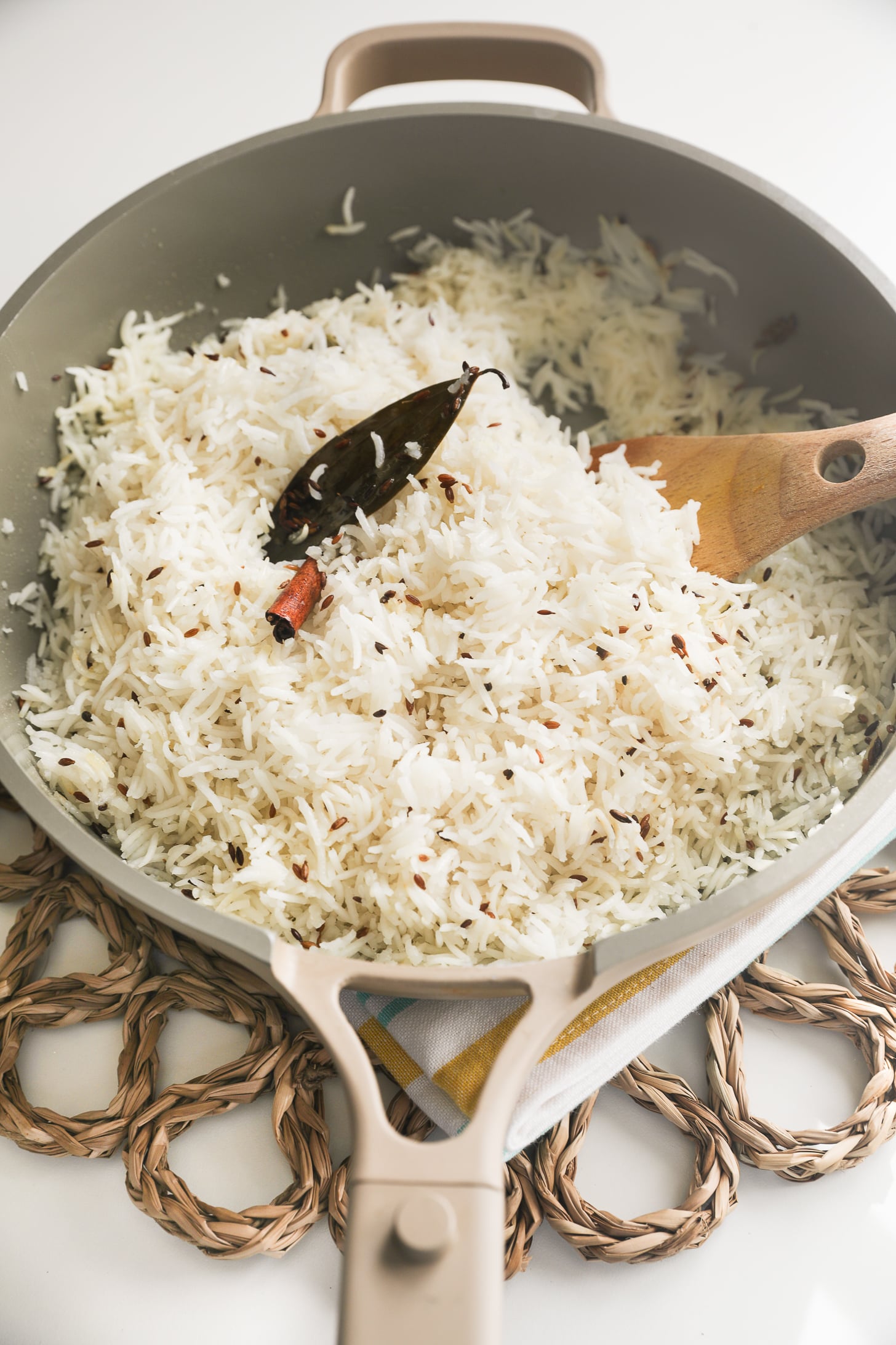 Basmati rice cooked with cumin, cinnamon stick and bay leaf in the pan.