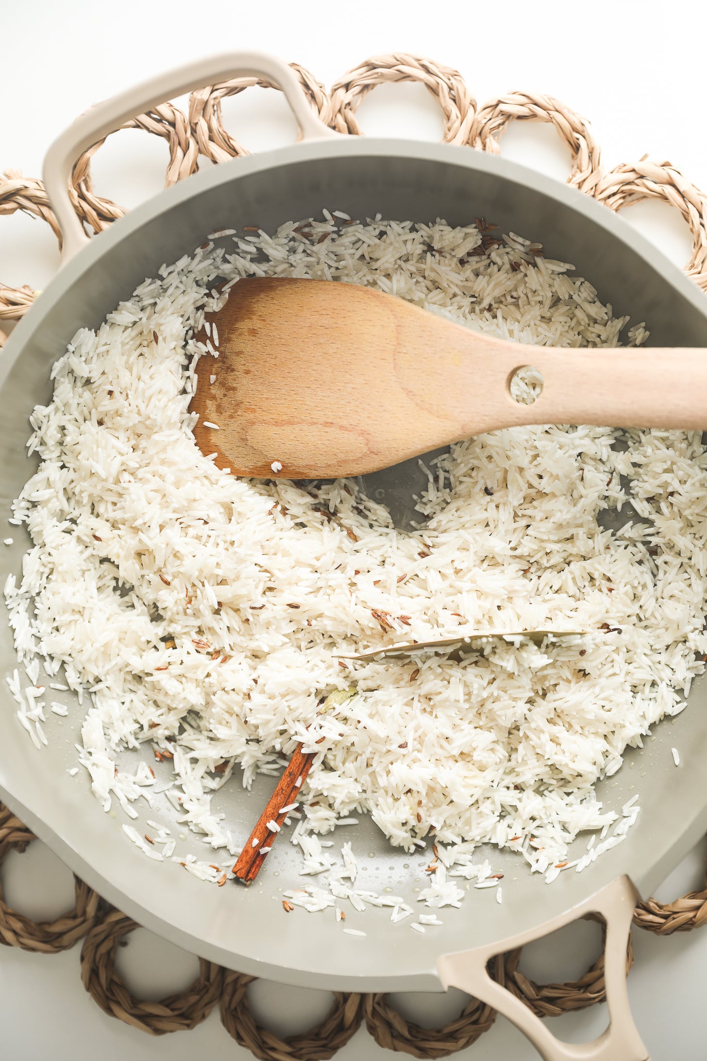 Rice coated with whole spices in a pan.