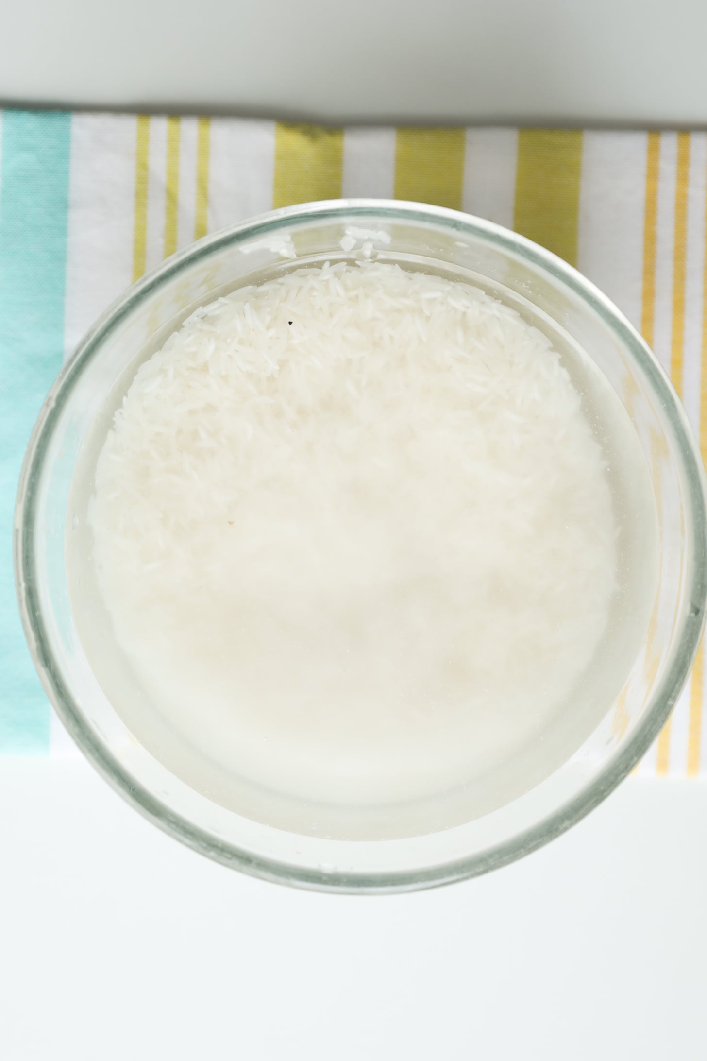 Rice soaking in water in a glass bowl.