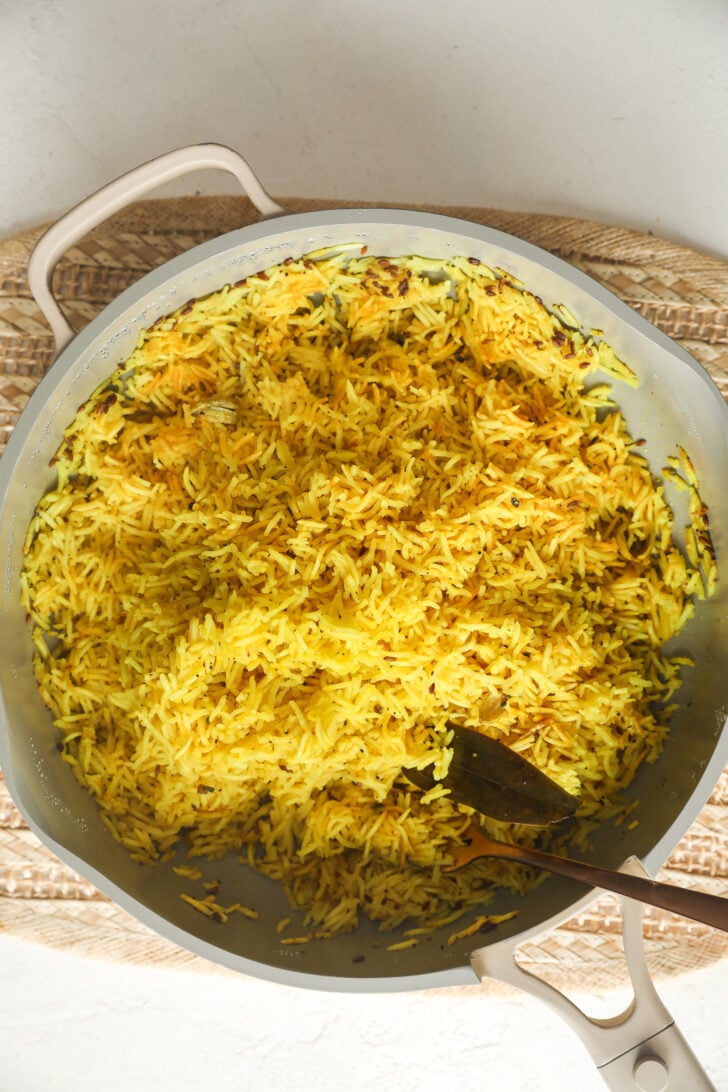 Riz au curcuma indien sur la cuisinière (si facile !) 10 Riz indien au curcuma cuit avec du laurier et des épices entières dans une poêle.
